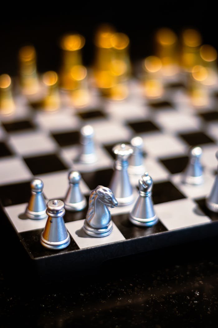 Close-up of a metallic chess set on a black and white checkered board, emphasizing strategy and design.