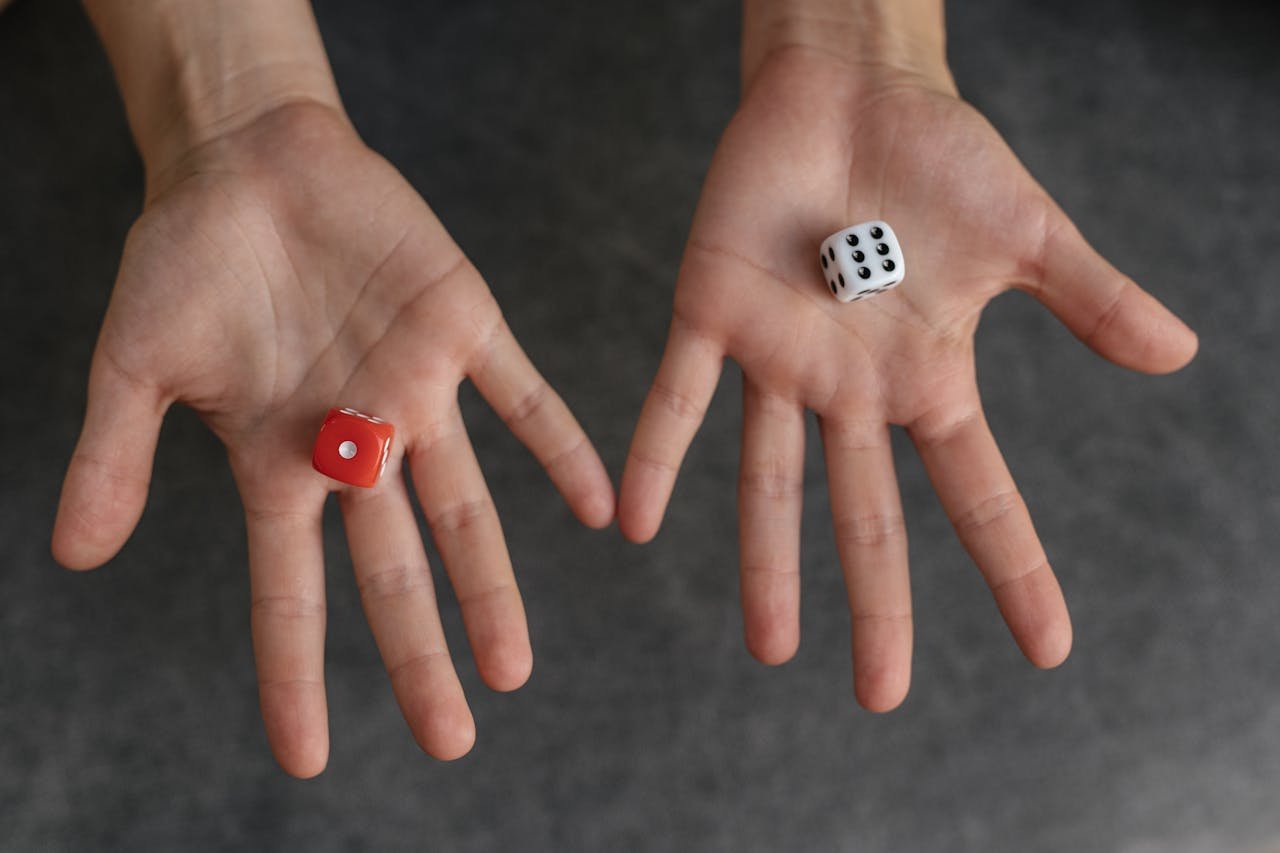 Close-up image of hands holding red and white dice against a blurred background.
